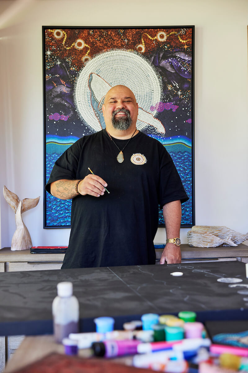 Aboriginal artists Garry Purchase in his studio with his artwork hanging in the background