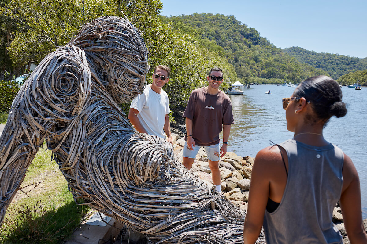 three travellers marvel at reed sculpture of woman