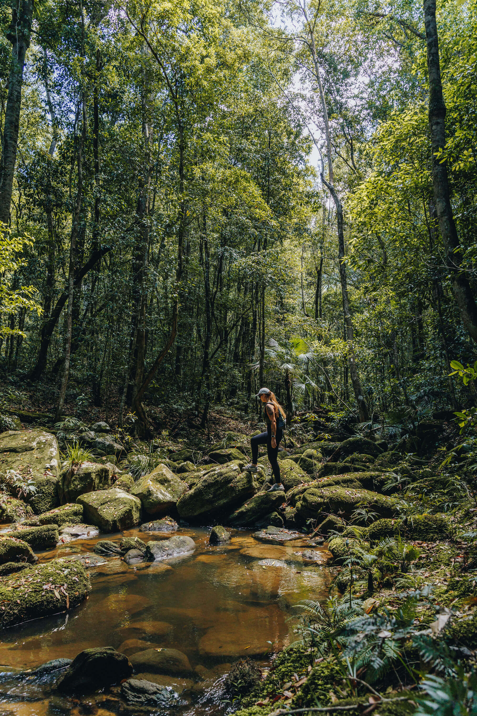 hiker crossing stream in forest