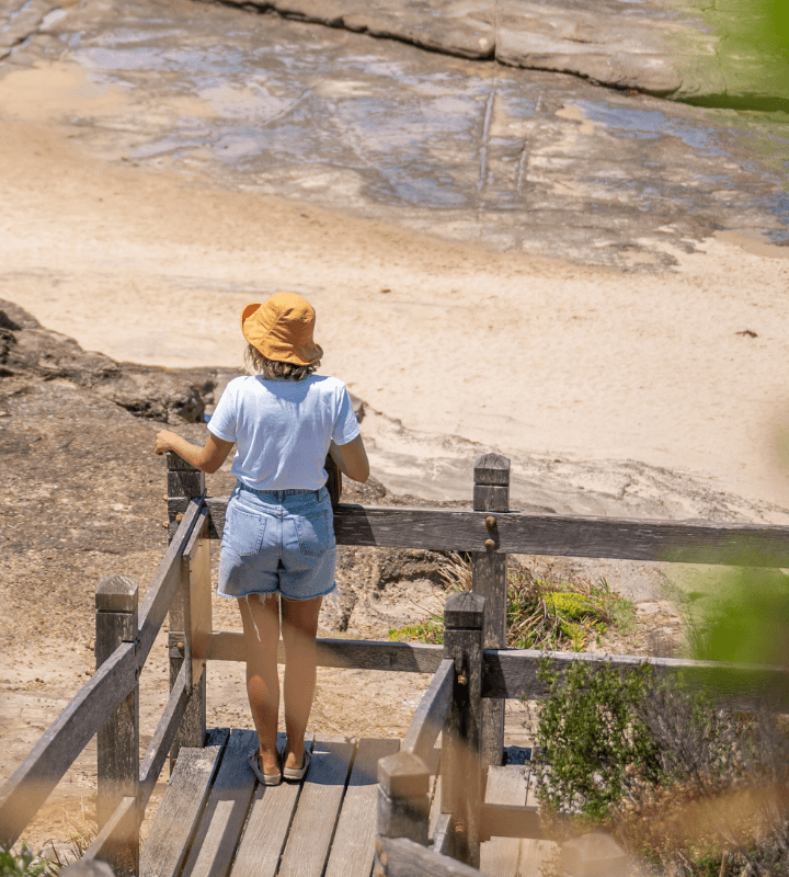 Women standing on wooden stairs overlooking a beach