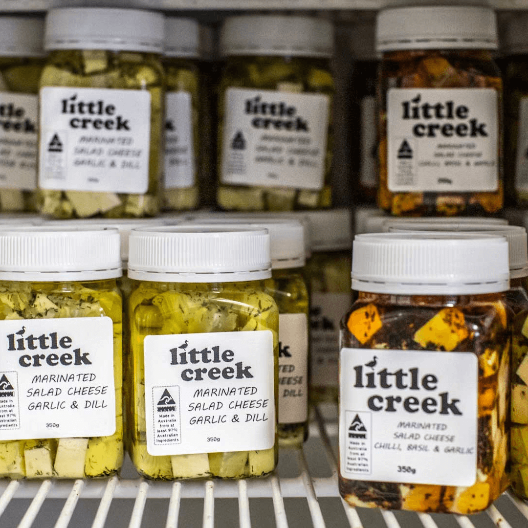 A fridge shelf filled with containers labelled 'Little Creek'. Each container is filled with cheese.