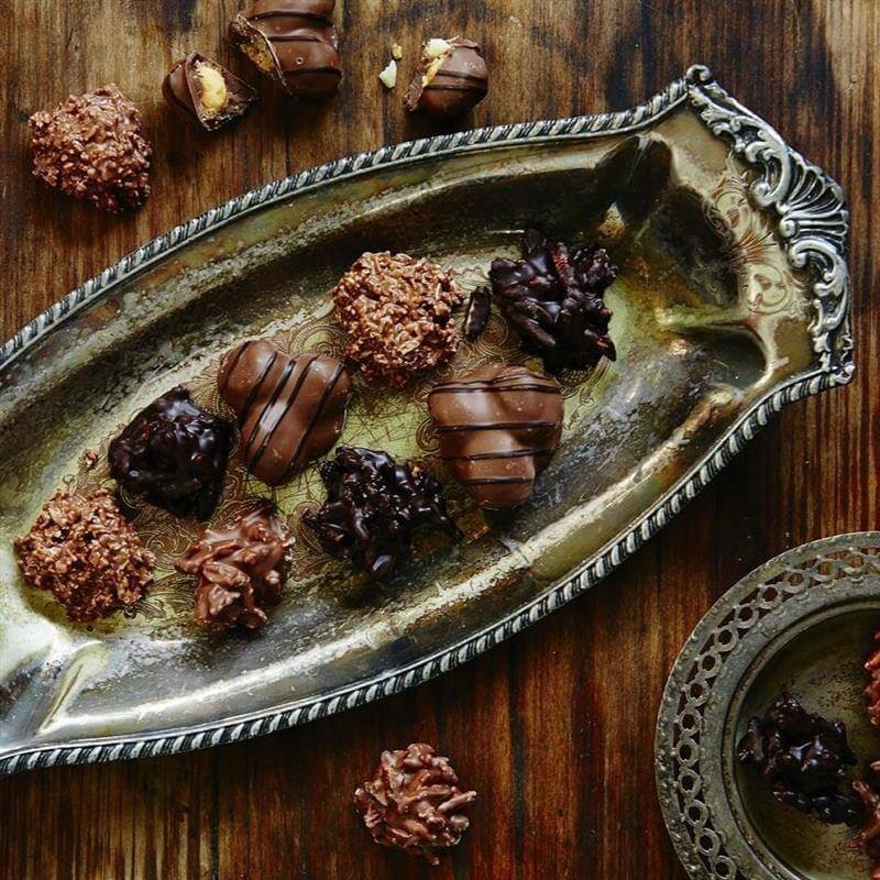 Vintage silver dish filled with artisan chocolates on a rustic wooden table