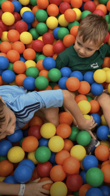 Two young boys play in a sea of colourful ball pit balls