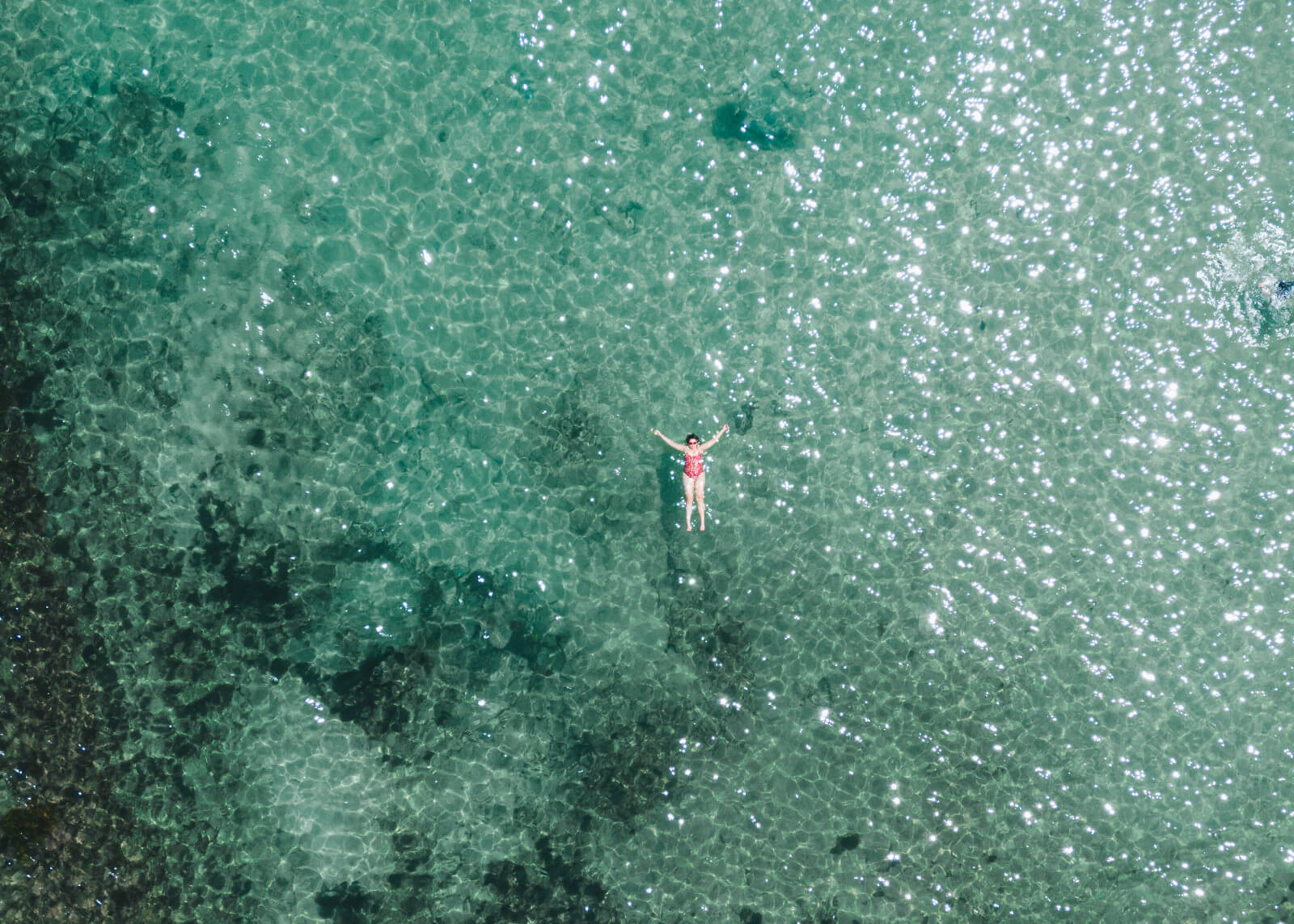 woman floating in swimmers on turquoise water