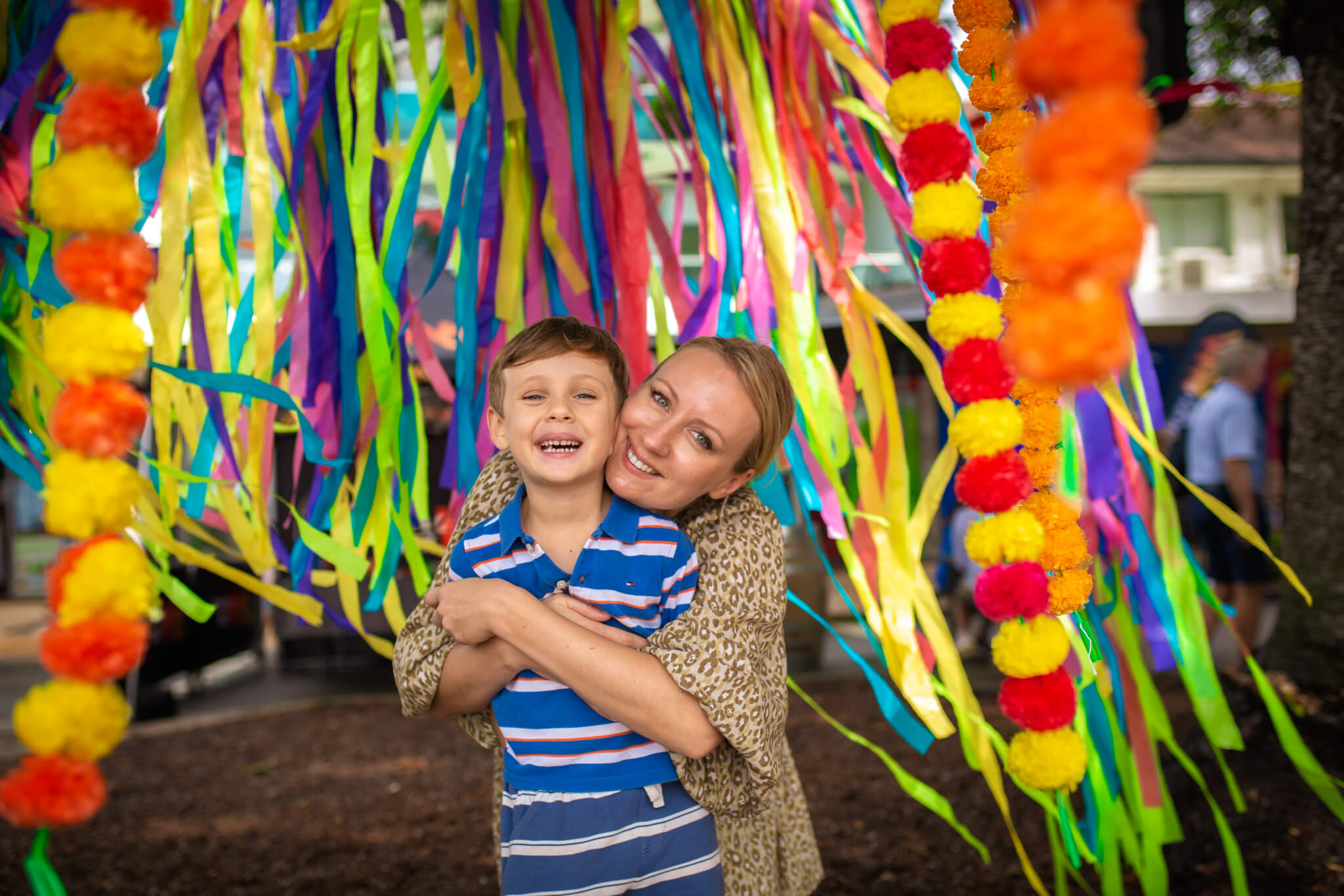 Woman hugging boy in front of colourful flags