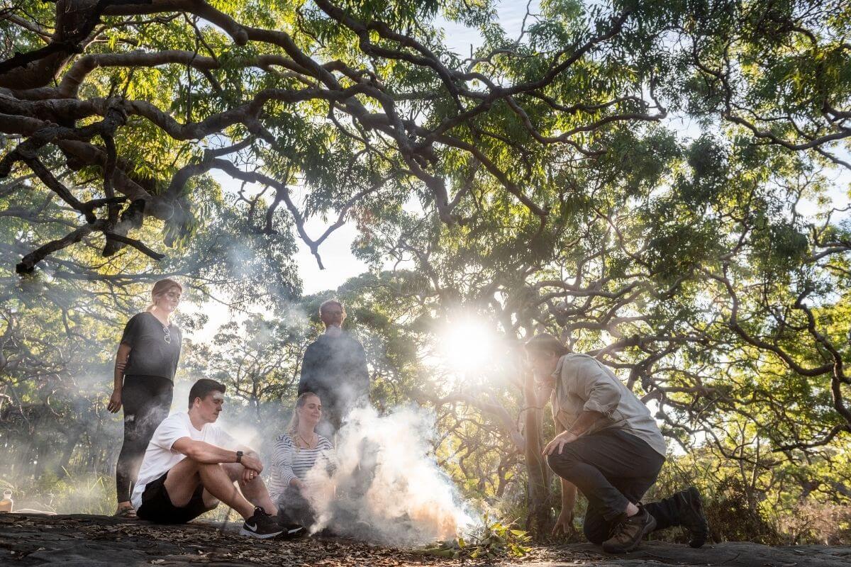 ecotourists embracing Aboriginal smoking ceremony in bushland