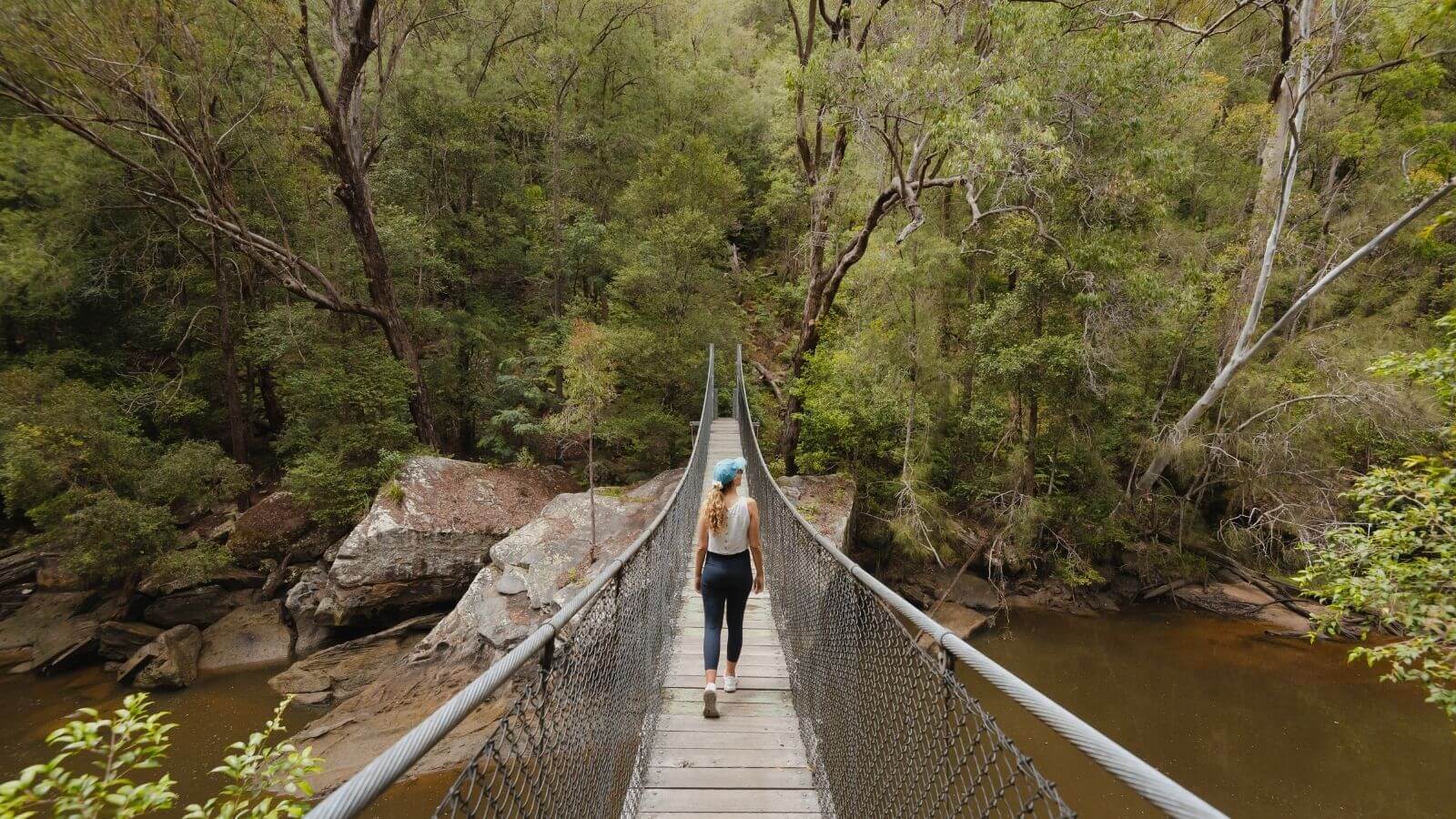 woman walking across suspension bridge in national park