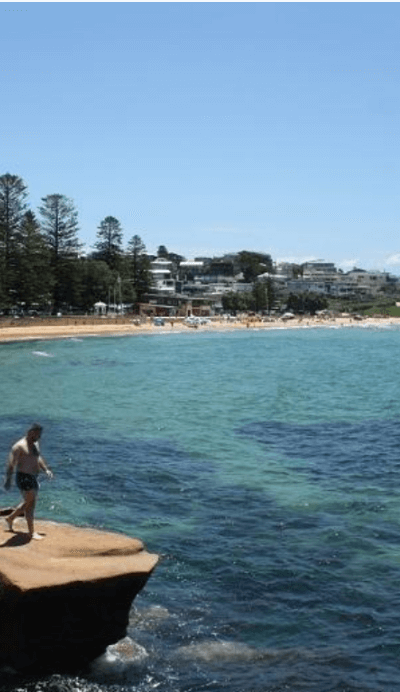 Man on rock with Avoca Beach in back ground