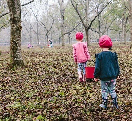 girls in field with red bucket