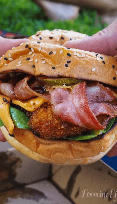 person holding massive burger up close