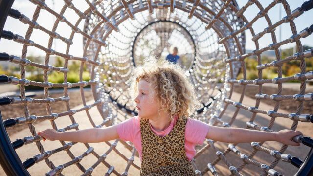 child in net playspace dappled in sunlight