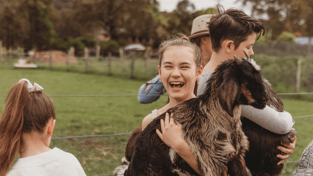 Giving Farm girl holding a baby goat