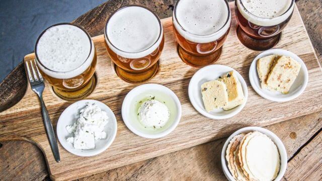 Paddle of tasting samples of fresh beers with cheeses 