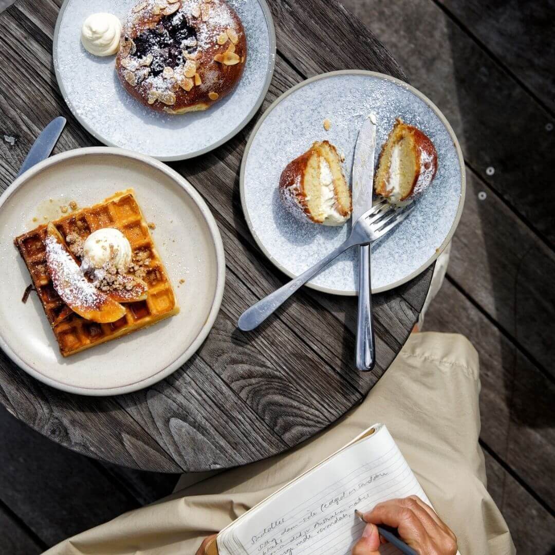 birds eye view of pastry table and woman writing travel journal