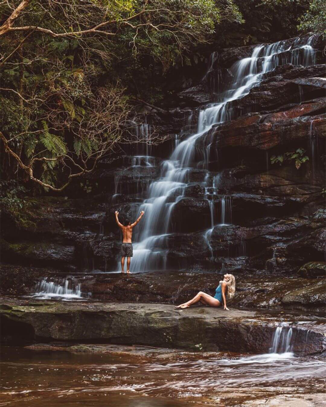 people paddling in waterfall