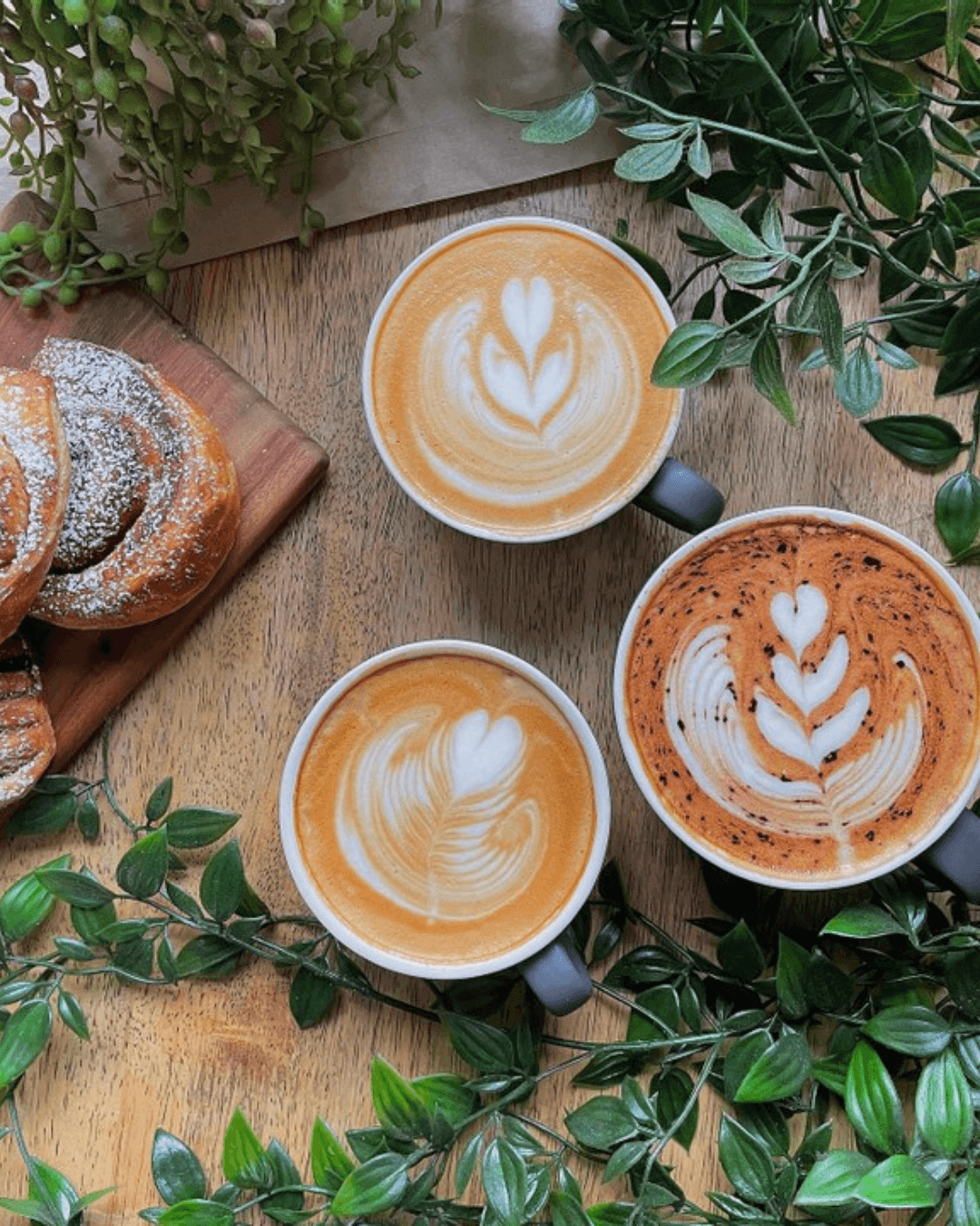 three milky coffees surrounded by leaves