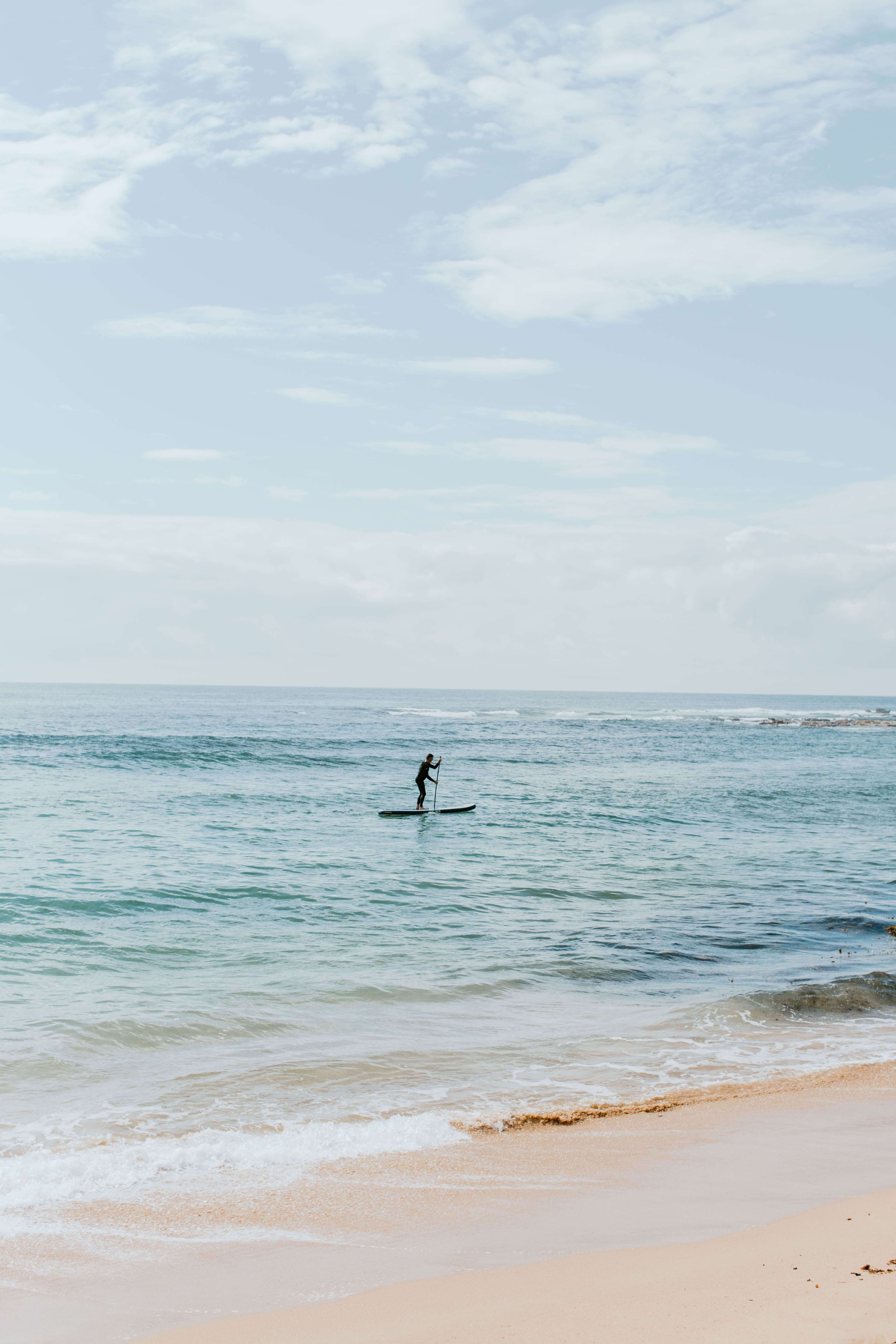 paddle boarder on water on calm afternoon bay