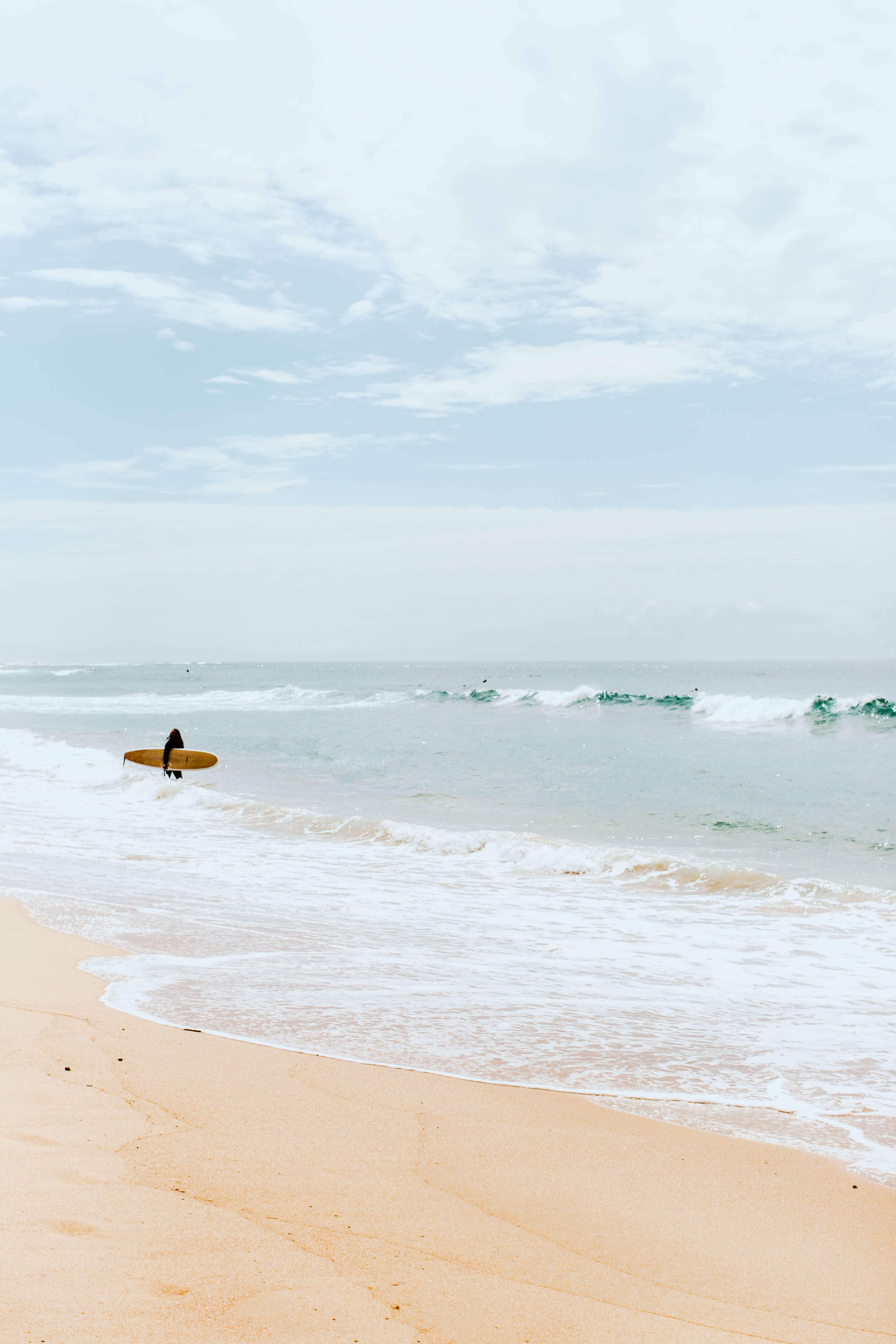 soft hues of beach shore as surfer enters water