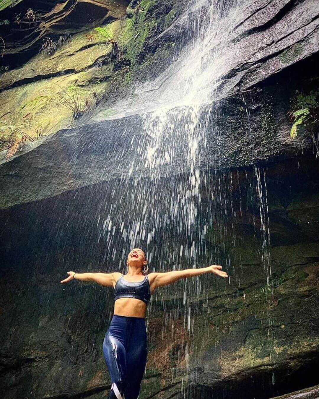 woman showering in natural waterfall cascade