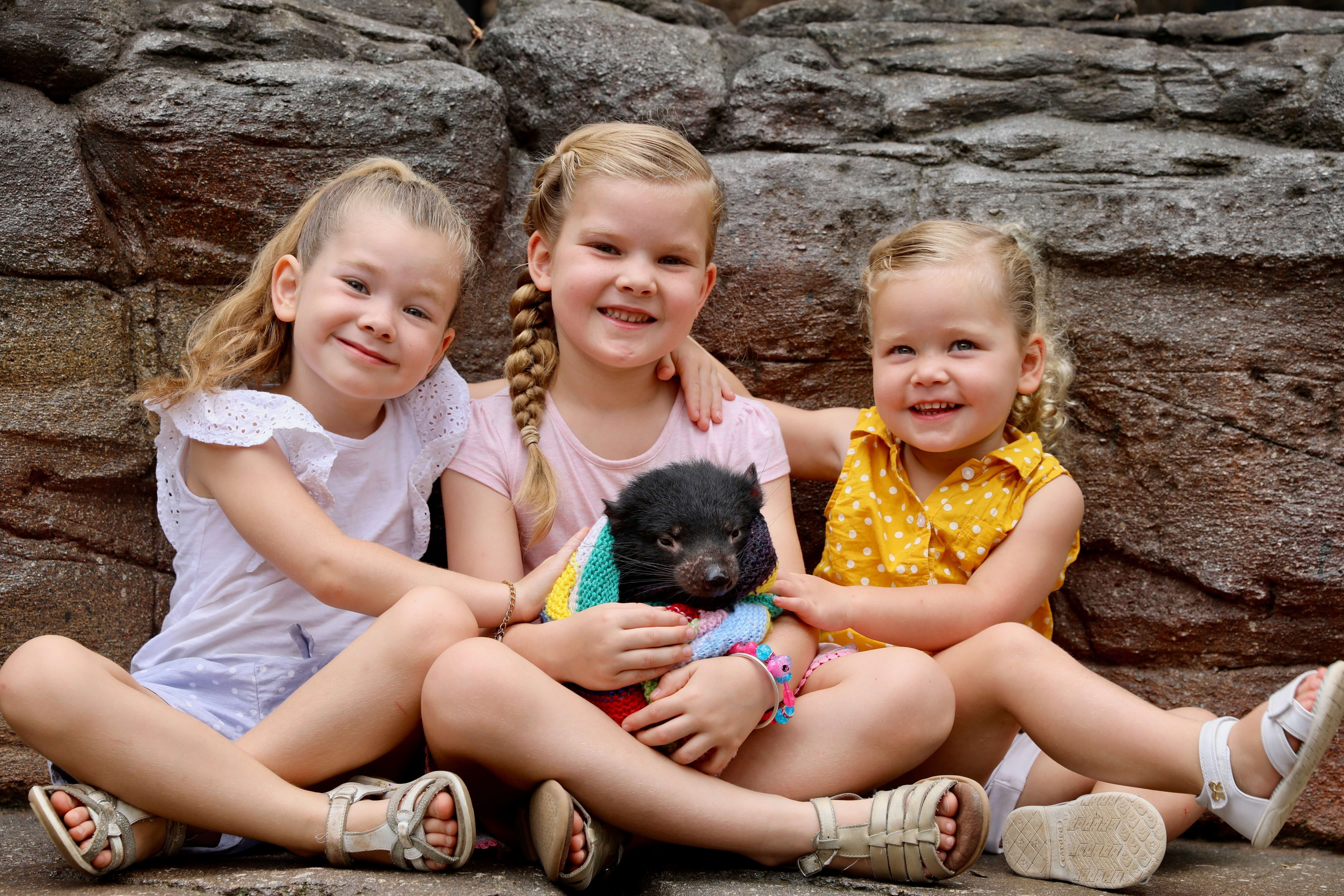 3 kids holding baby tasmanian joey at Australian Reptile Park