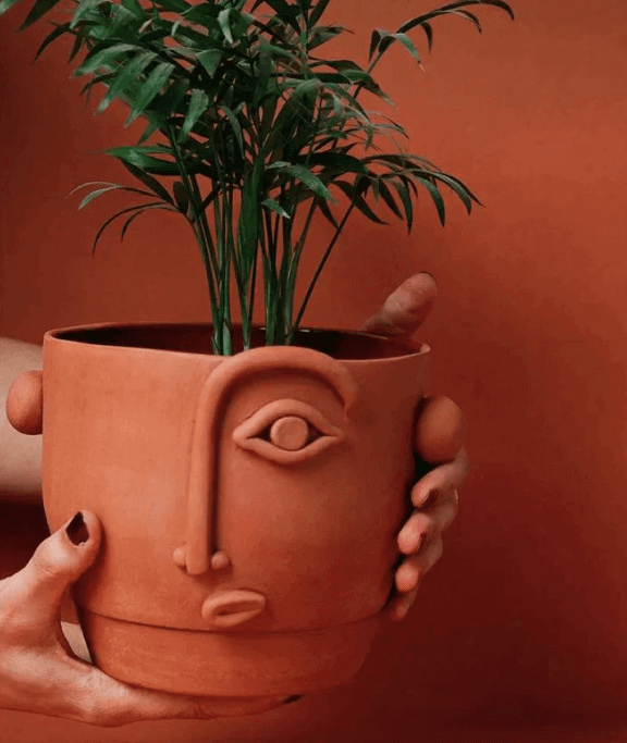 Handmade pot with clay face on it