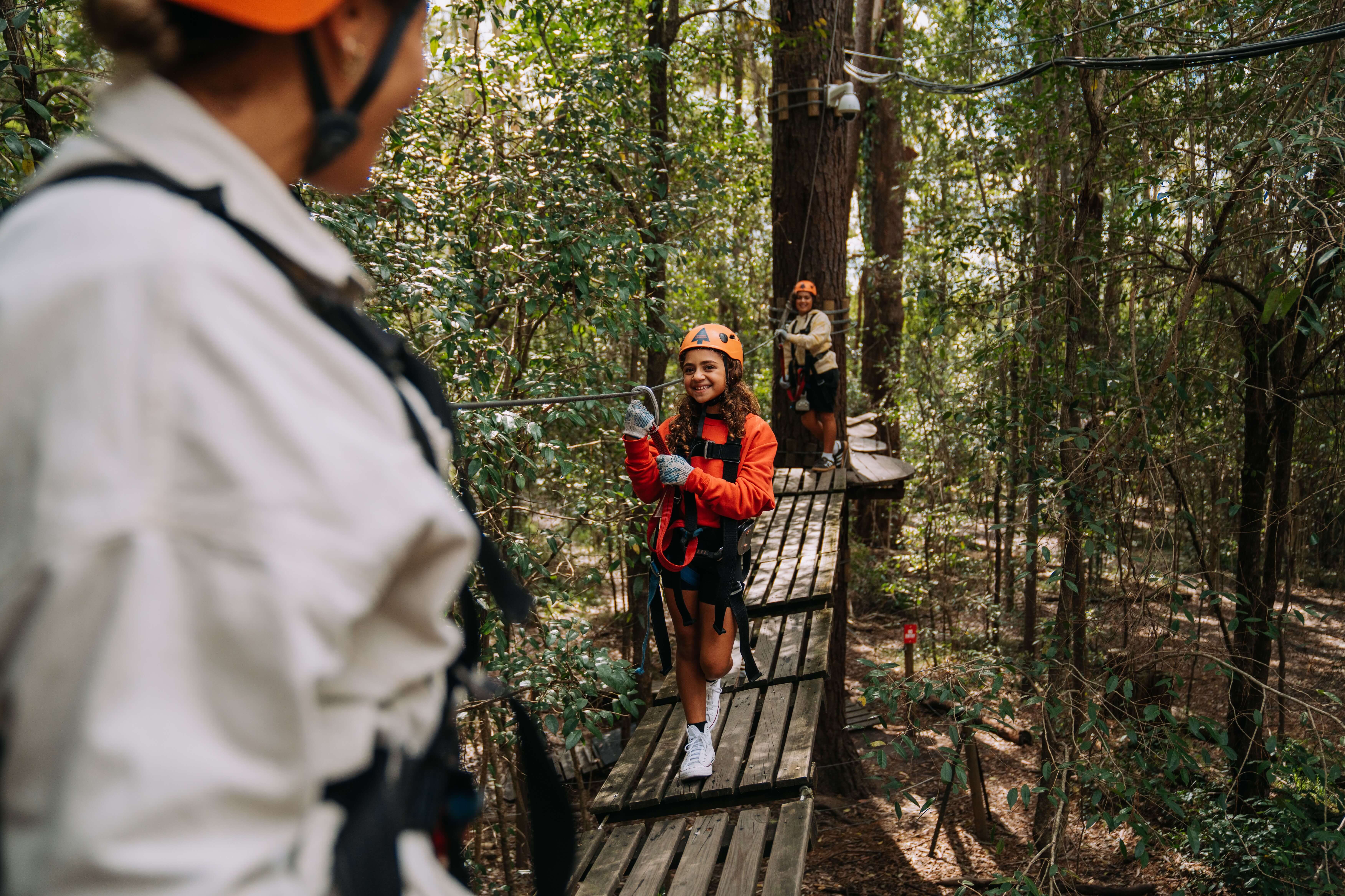 Kids and adults climbing along a rope path through the bush