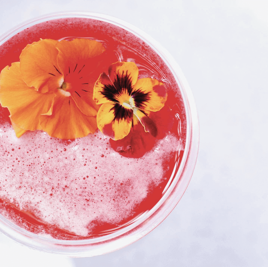 Pink cocktail with yellow flower in glass