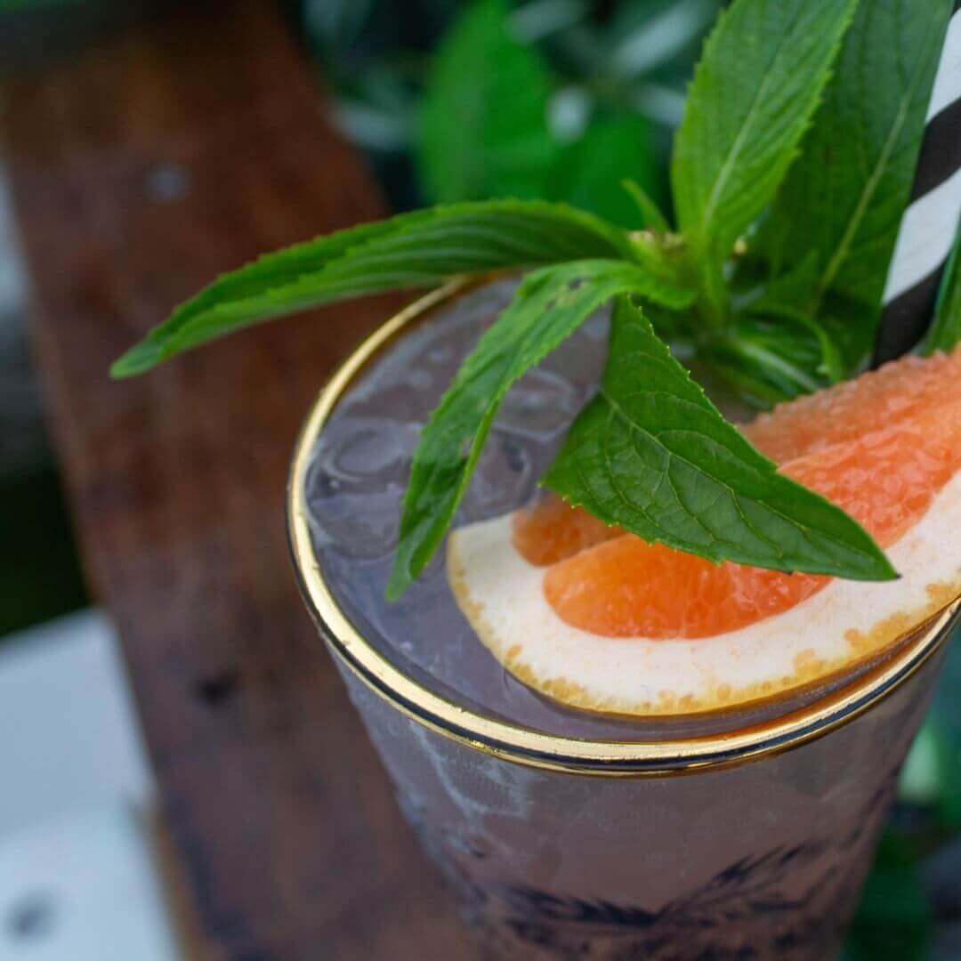 Cocktail on wooden table with slice of orange and mint leaves