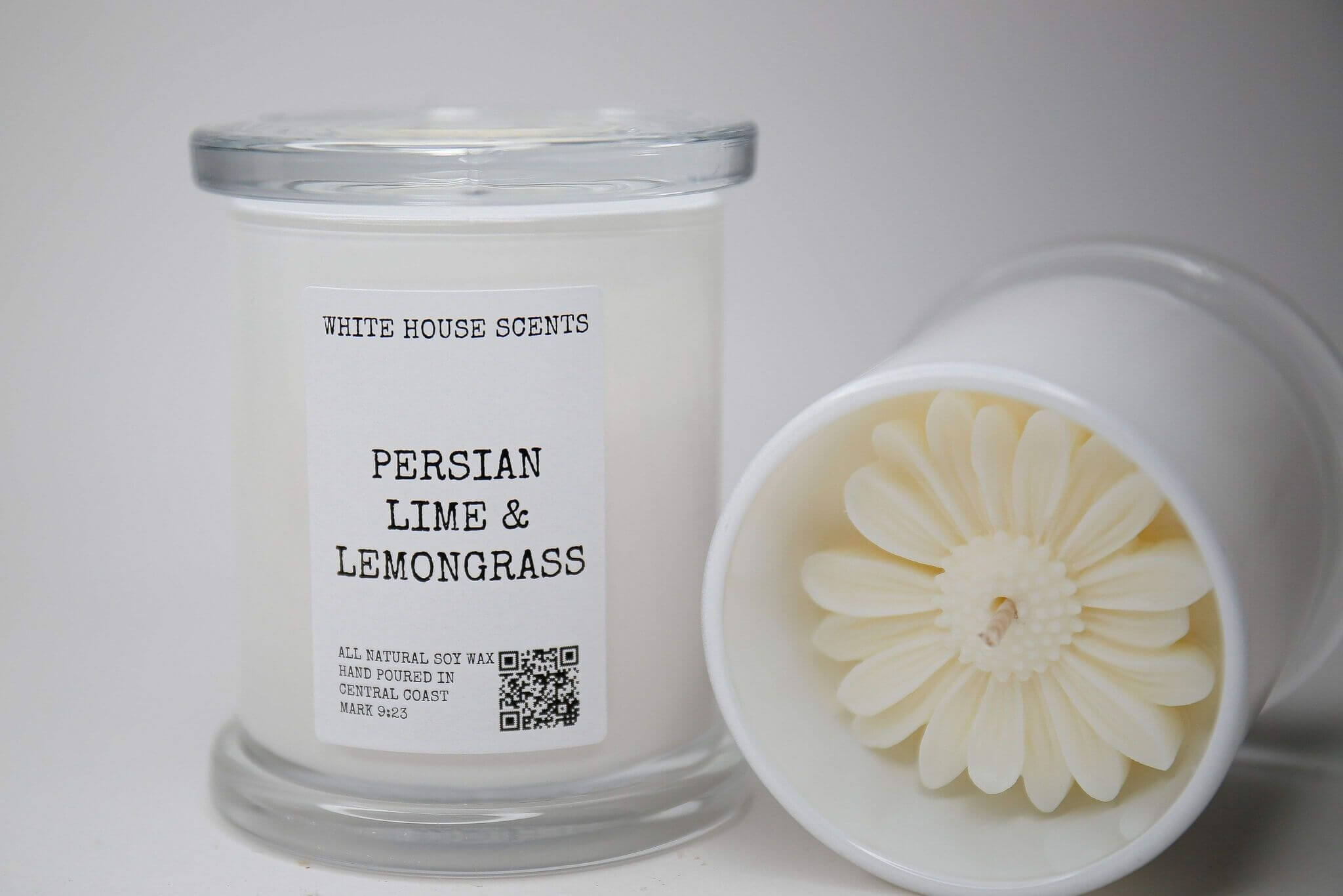 A candle lays on its side, as a candle stands next to it labelled "Persian Lime and Lemongrass"