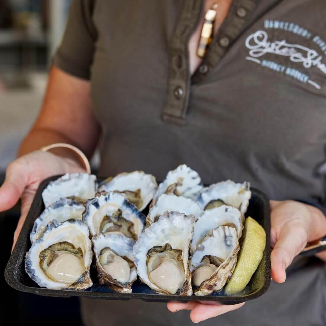 A lady holding a dozen oysters