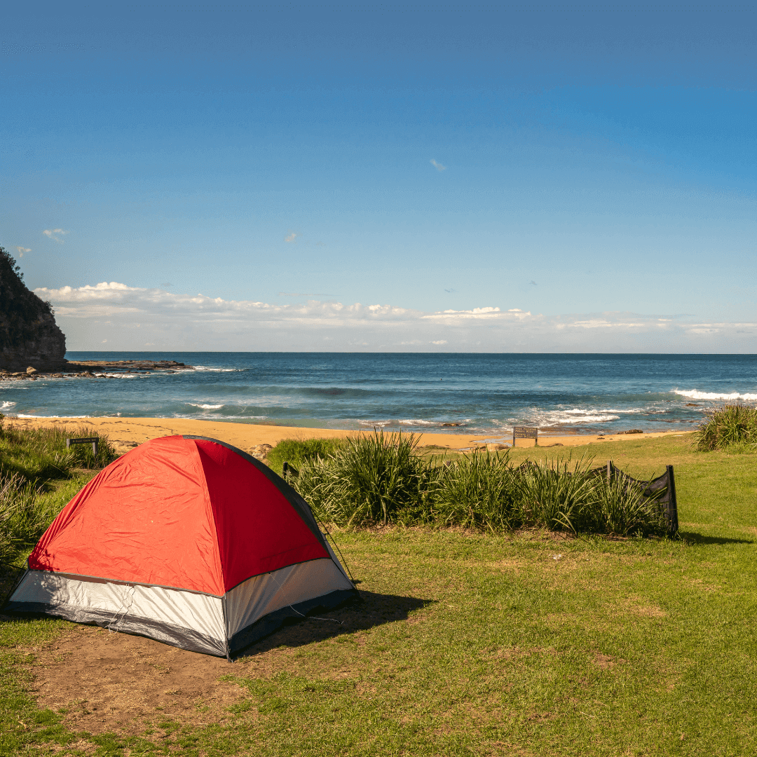 A red tent sitting on a green grounds overlooking a beach