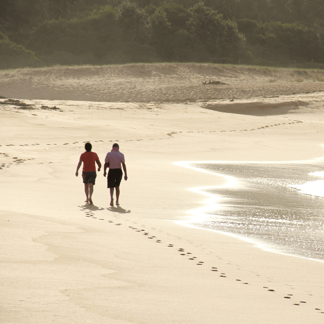 A couple walking along the golden sands of a beach