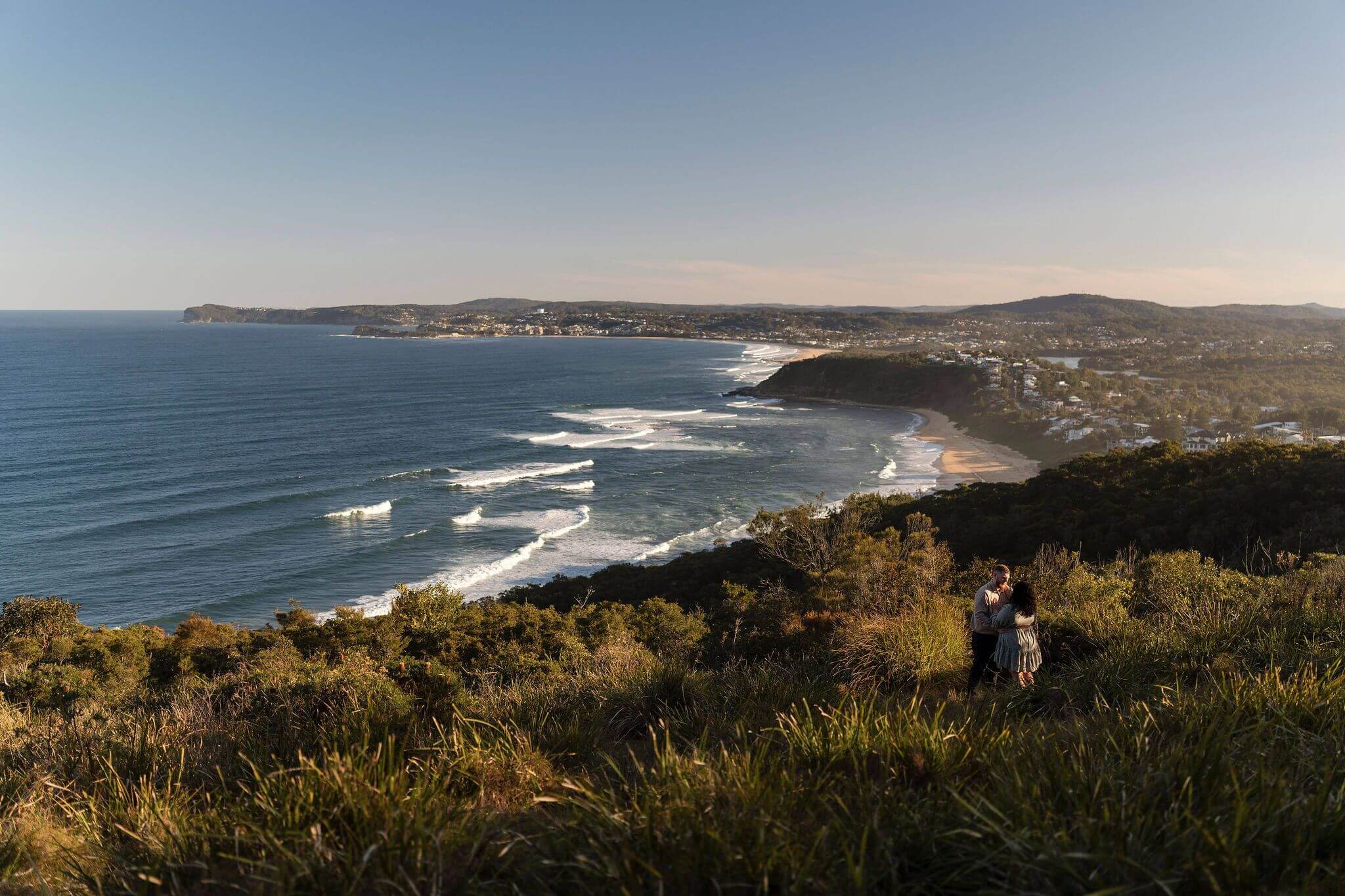A couple standing amongst the grass of a lookout