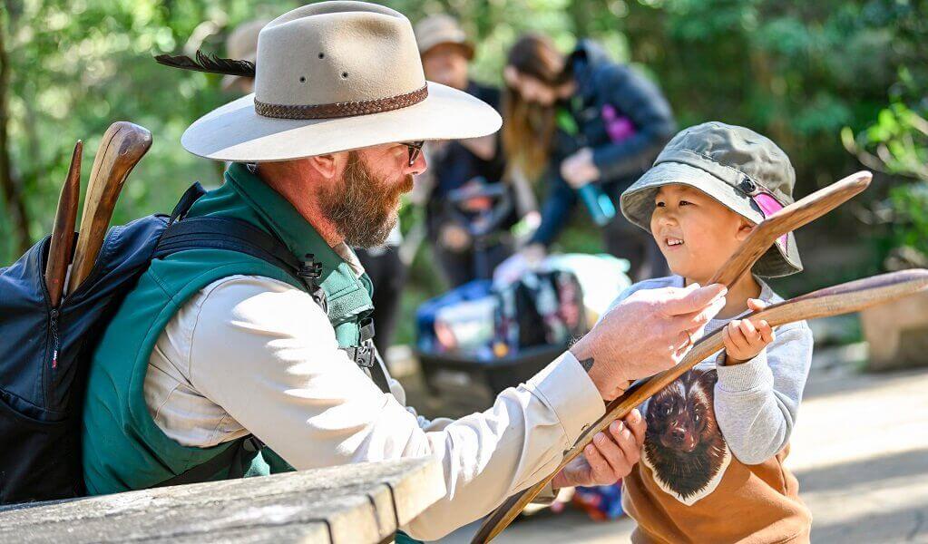 A ranger shows a child how to hold a boomerang