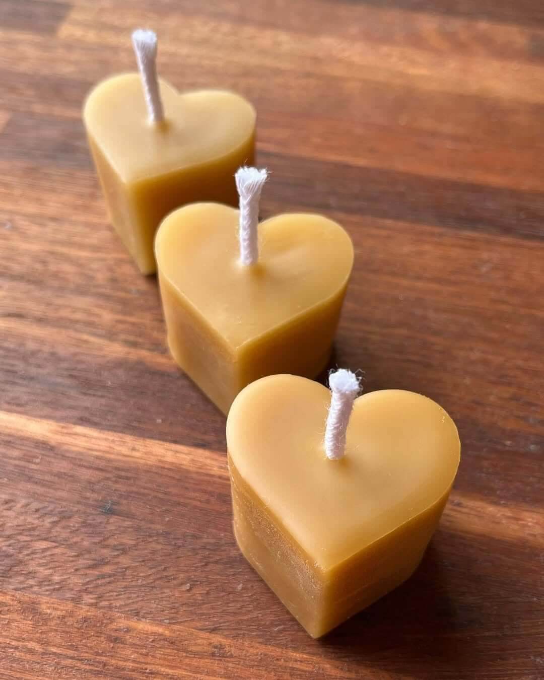 A set of three honey-yellow love heart shaped candles with a white wick