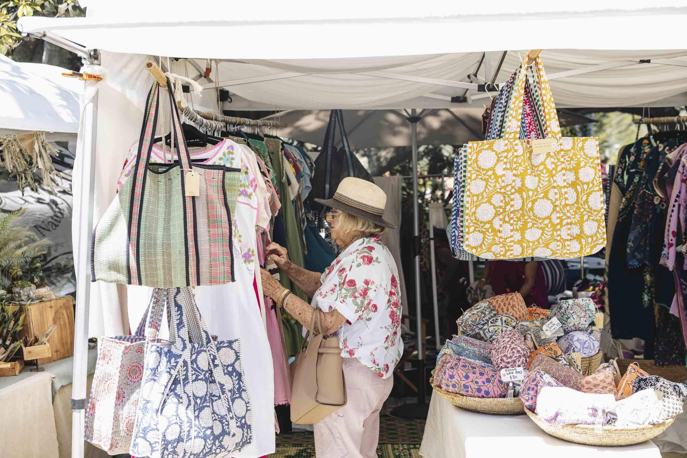 An older lady looking at handmade bags in a market stall