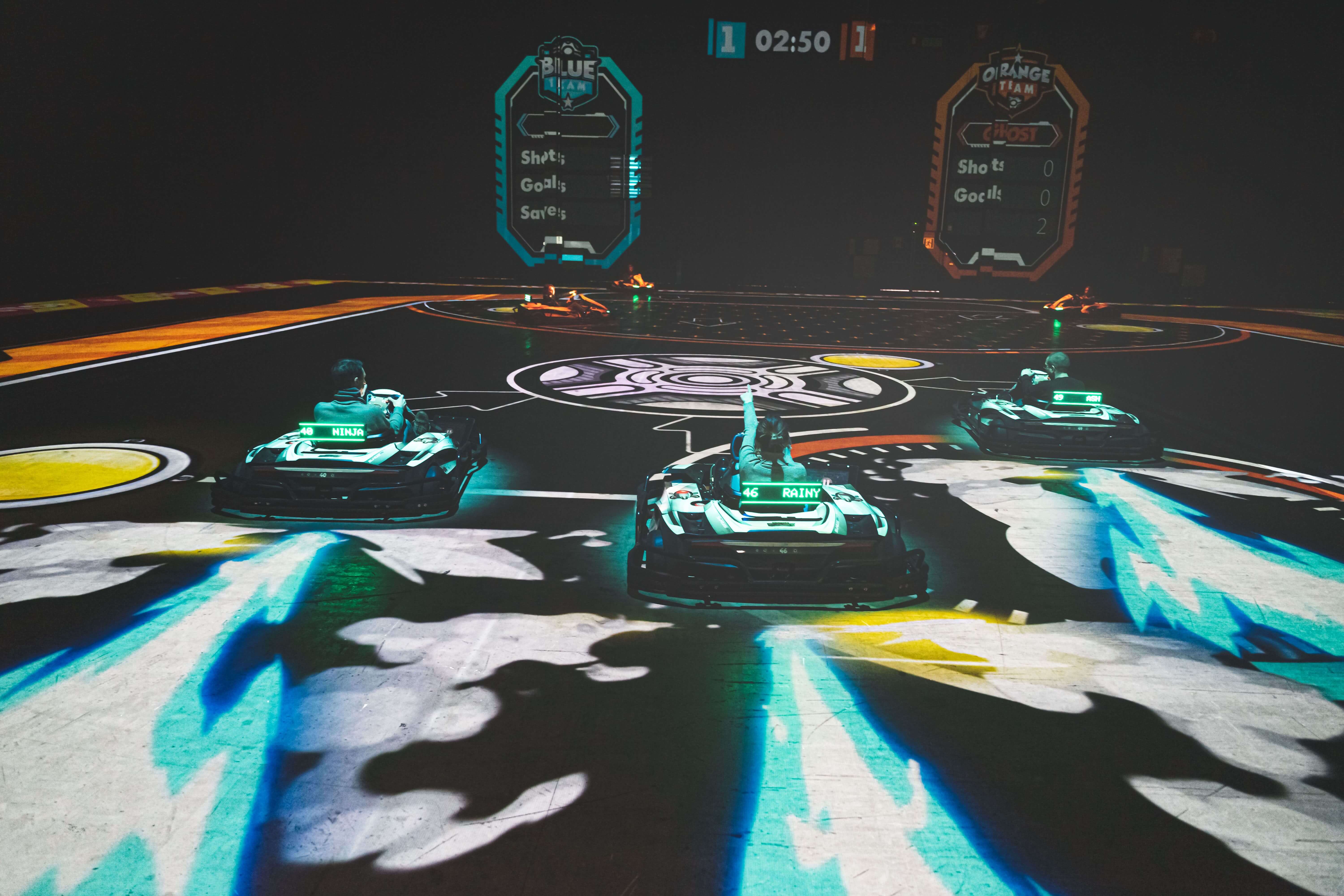 A neon-lit track with three people riding electric karts.