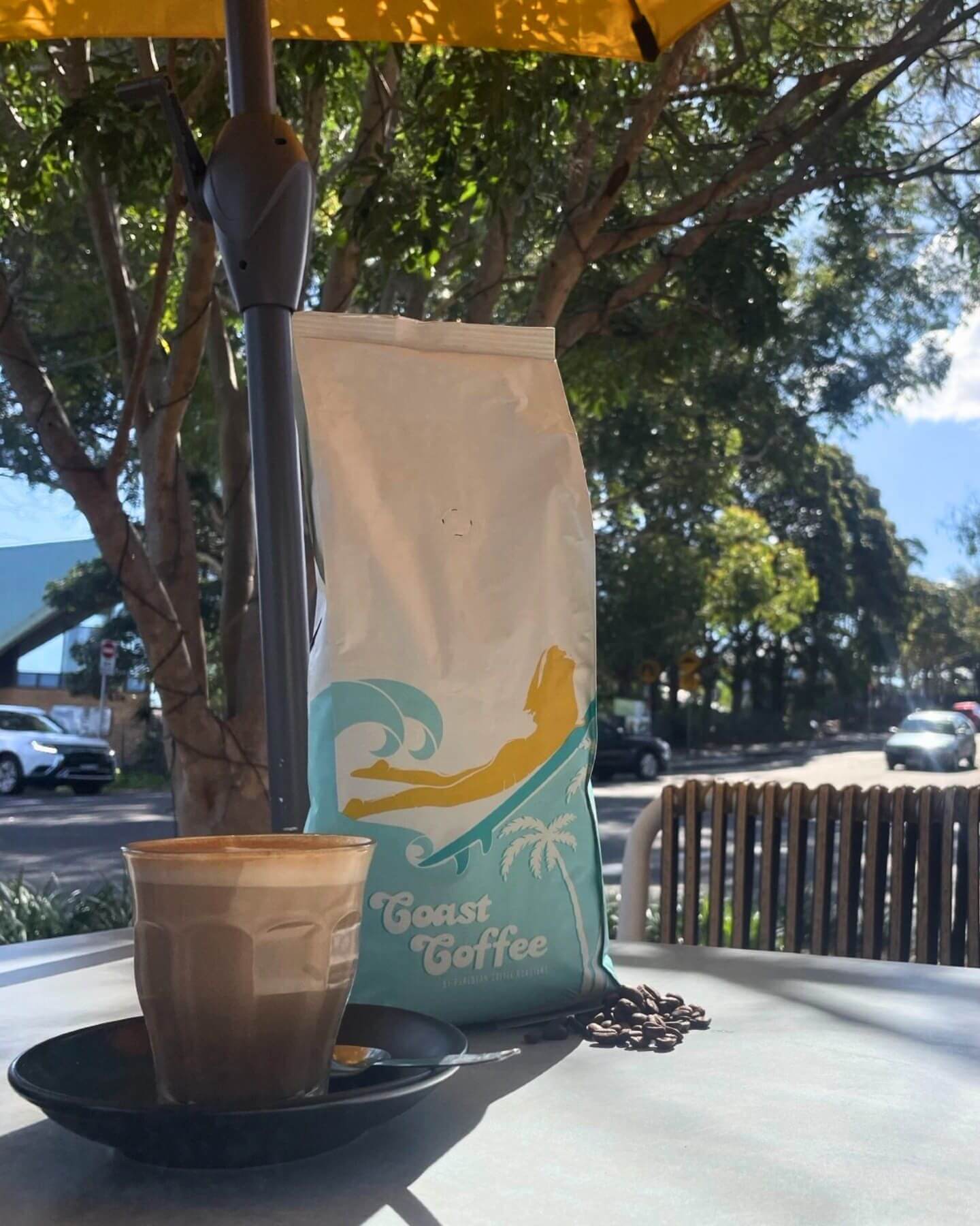 A bag of coffee beans and a coffee sits perched on a tabletop.