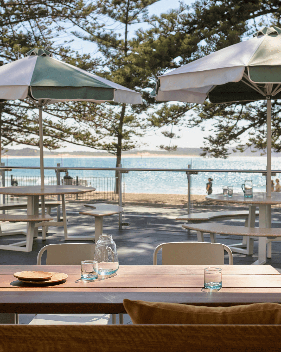 two seats looking out at beachfront esplanade with umbrella shade