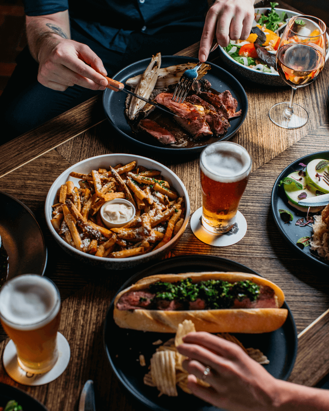 overlooking food filled pub table with hands grabbing chippies