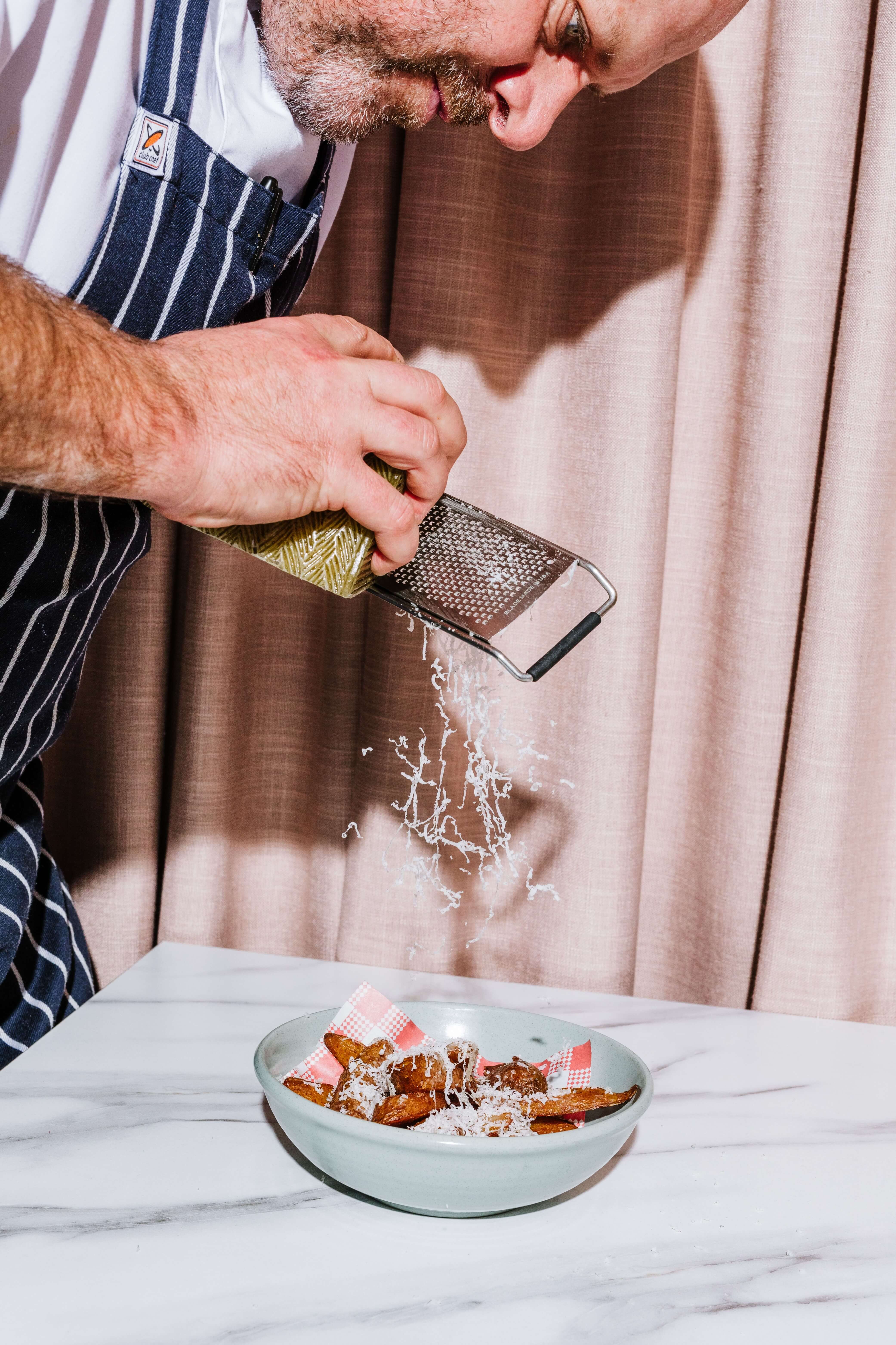 chef grates cheese on dish