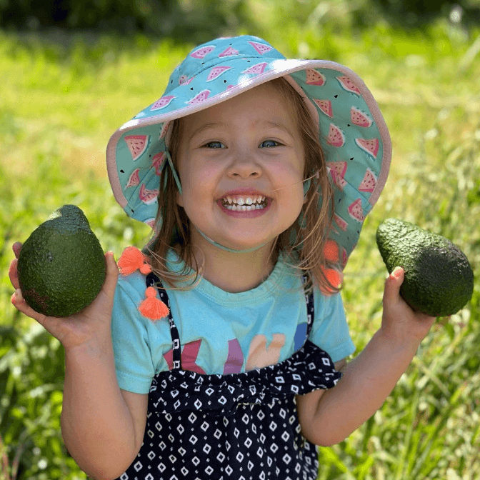 Girl holding two freshly picked avocados