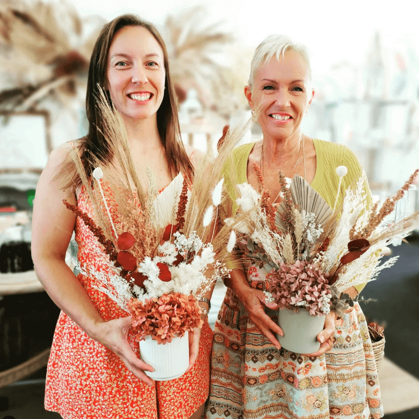 two women holding preserved floral arransgment 