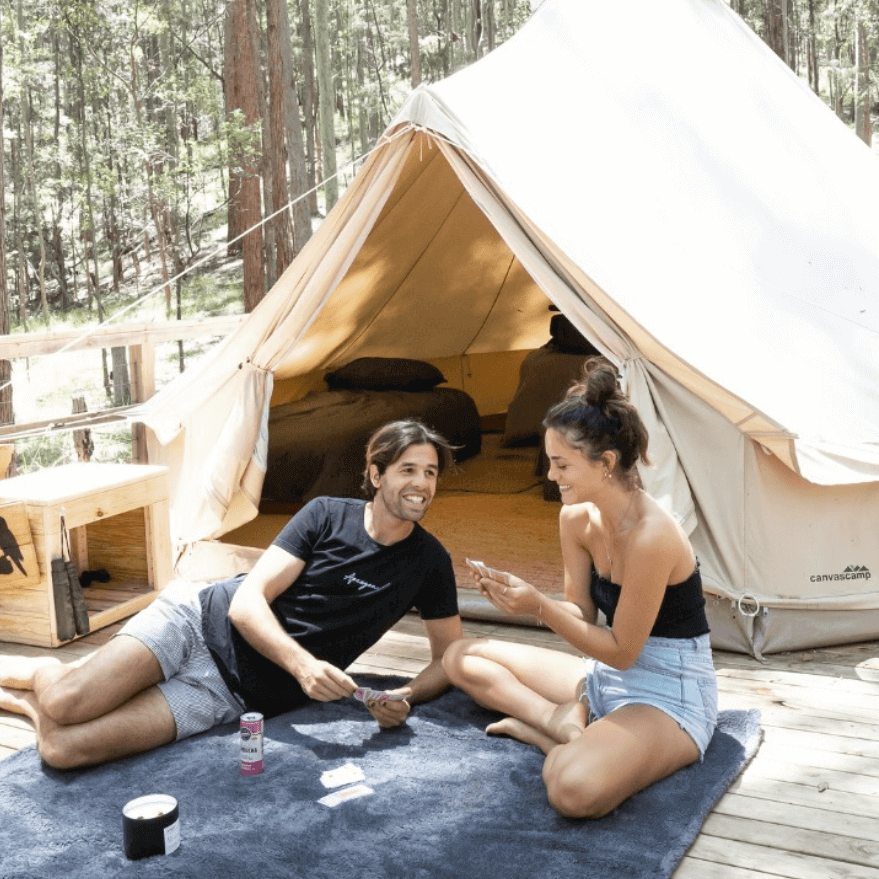 Couple outside playing cards infront of glamping tent