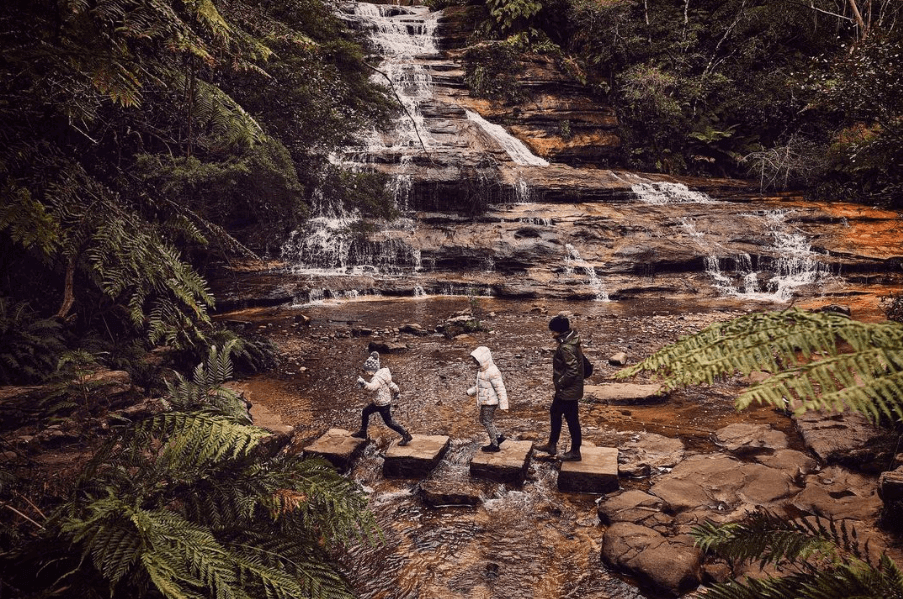 kids in winter clothing stepping over stepping stones