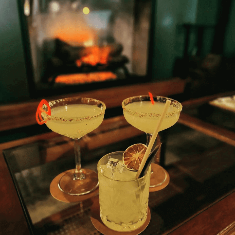yellow cocktails in front of log fire