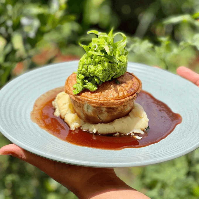 Pie on a bed of gravy and mash