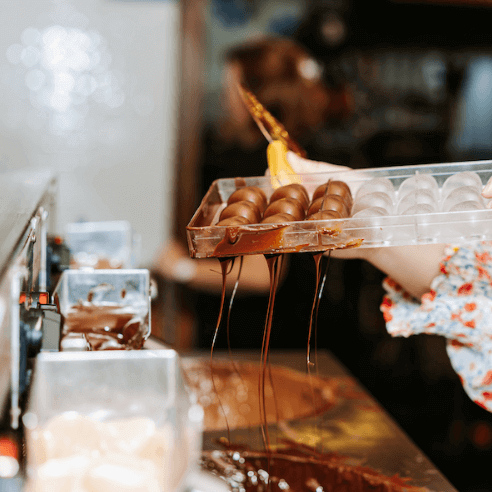 Lady filling chocolate mold with milk chocolate