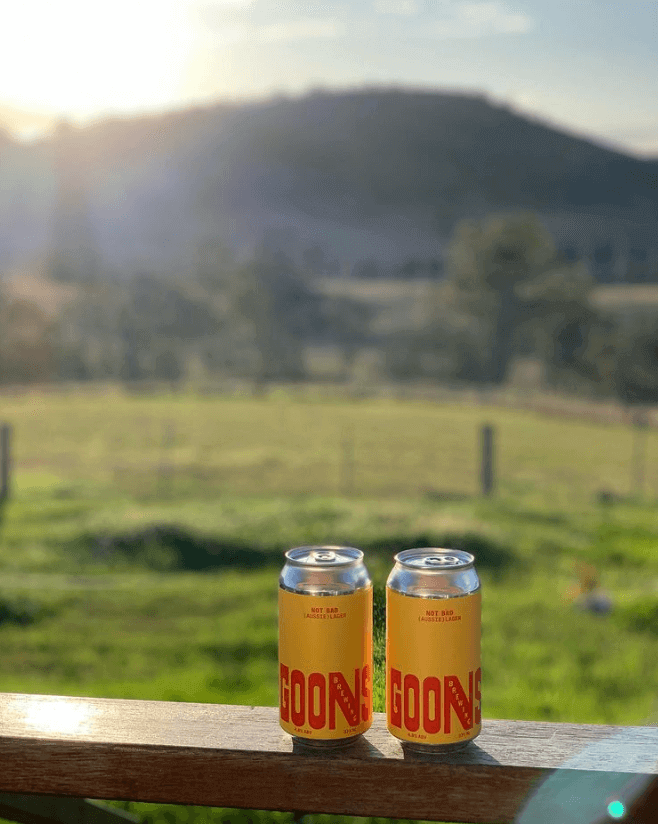 two craft beers on a farm fence