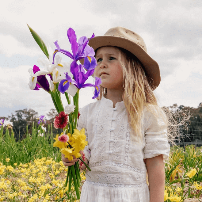 little girl holding hand picked flowers